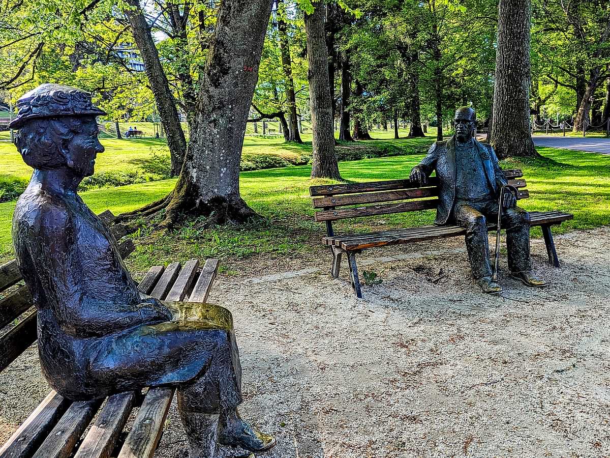 Kurpark Bad Orb mit Bronzestatuen auf Bänken unter alten Bäumen